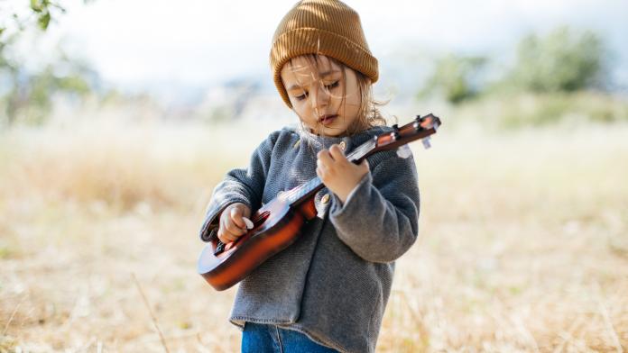Litlle girl playing guitar instument kinderen muziekles
