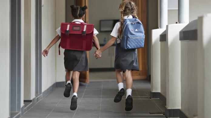 Schoolgirls running hand in hand on the isle of school and laughing bewegend leren zitten school