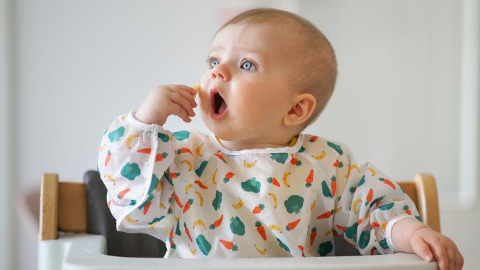 Little baby eating her snack herself slab met mouw eerste hapjes eten