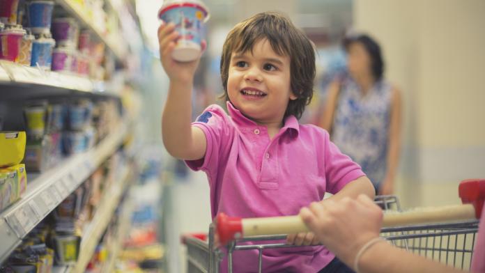 Young boy smiling, sitting in a shopping cart neen zeggen opvoeding positieve formulering