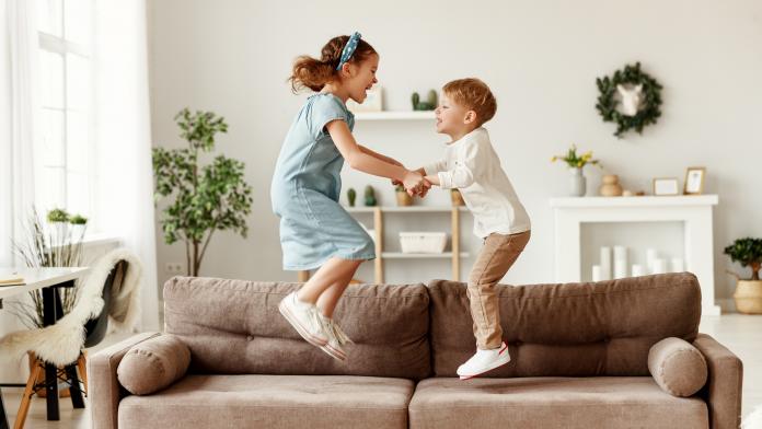 Happy siblings jumping on sofa kindvriendelijk interieur veilig speelruimte