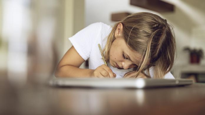 Girl sitting at table writing into diary kinderdagboekjes om om te gaan met maatschappelijke druk en stress