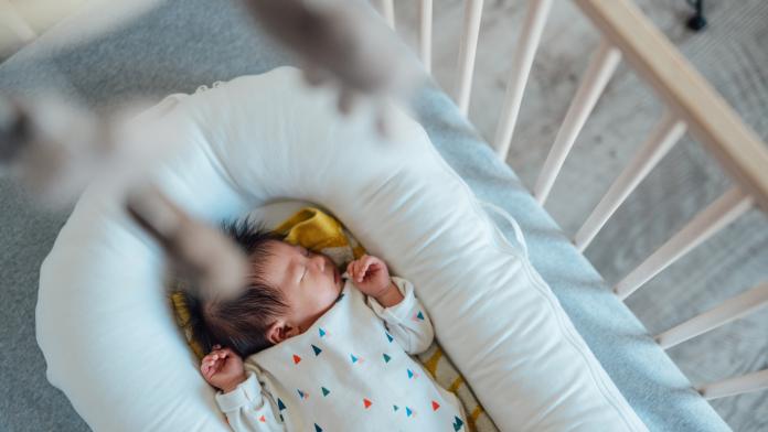 Cute Asian Baby Sleeping In Crib babynestjes cocoon geborgen gevoel