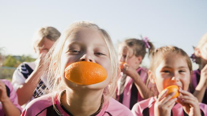 Girl soccer players eating orange slices sport aangepaste voeding voedingsexperte