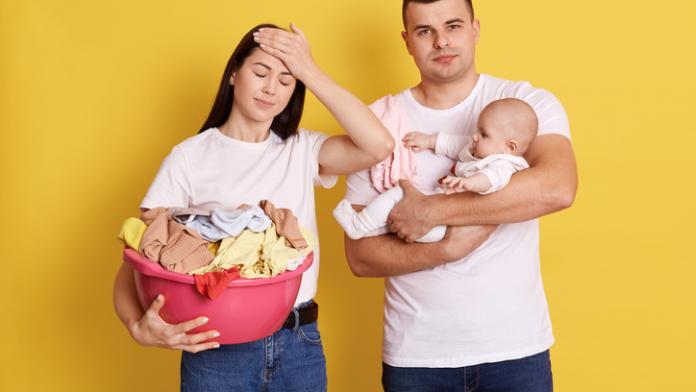 Tired parents doing household chores and taking care of newborn baby, mother holds basin with linen, keeps eyes closed and touch forehead with palm, father carries daughter with exhausted expression. week van de kraamzorg