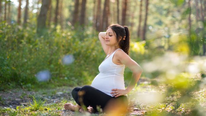 Portrait of happy pregnant woman outdoors in nature, doing yoga exercise. sofrologie ontspannen zelfzorg