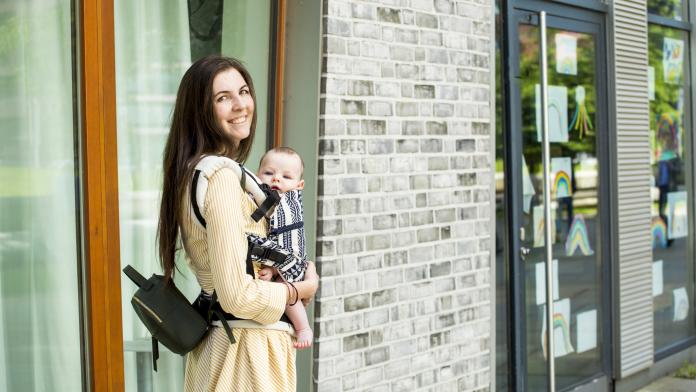 Smiling mother with her baby boy in baby carrier in city kindje dragen last van rug