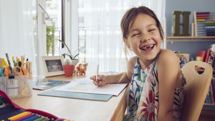 Happy girl doing her schoolwork at home kinderbureau bureau huiswerk kinderkamer slaapkamer