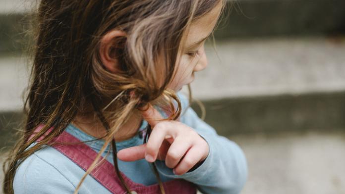 portrait of a beautiful little girl twirling her hair introverte kinderen