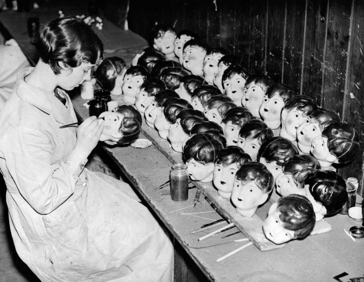 Une employée peint le visage des poupées