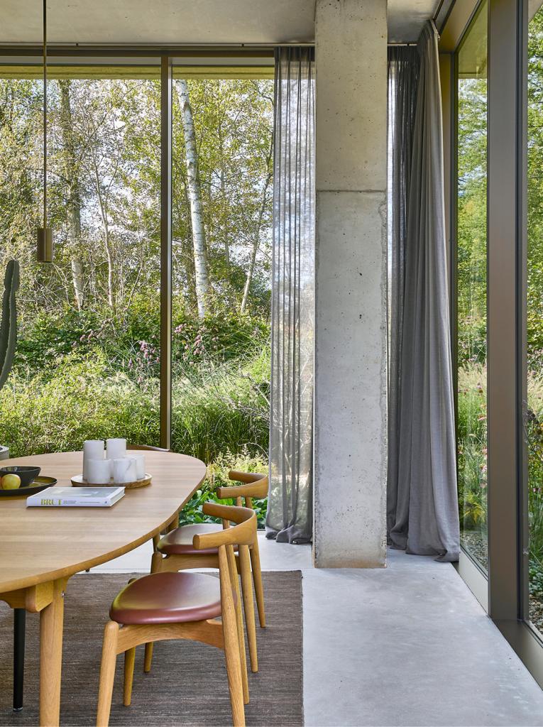 In de eetkamer is er buiten een schaal en een paar kaarsen op tafel niets om je af te leiden van de omringende tableaux vivants. Rond de eettafel staan Elbow Chairs van Carl Hansen & Søn. De lampen  en armaturen in de woning zijn ontworpen door Hans Verstuyft.