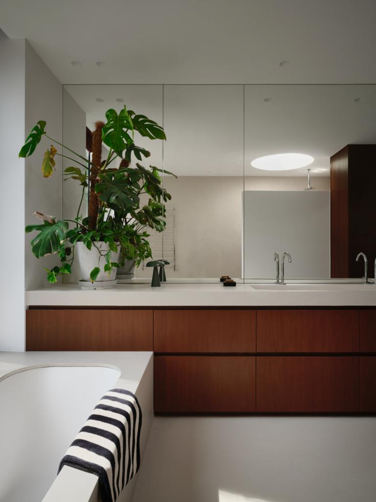 Het eikenfineer van de keuken komt terug in de badkamer. Onder het ronde dakraam bevindt zich een inloopdouche.