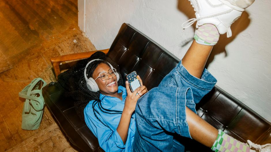 femme canapé casque et téléphone, jambes en l'air