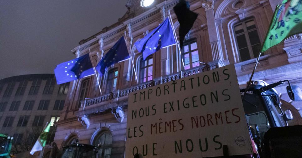 une manifestation d'agriculteurs devant des drapeaux de l'Union européenne