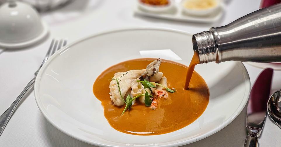 Pouring the lobster bisque into the bowl.