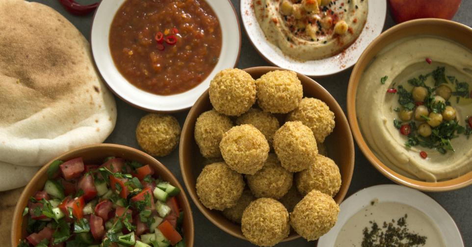 Authentic food of Israel: hummus, falafels, pita bread and fresh fruits. Dark grey background with copy space. Healthy eating concept.