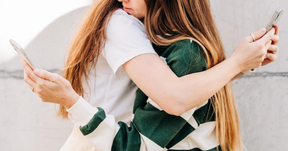 People live on social networks. Two people using phone at the street.