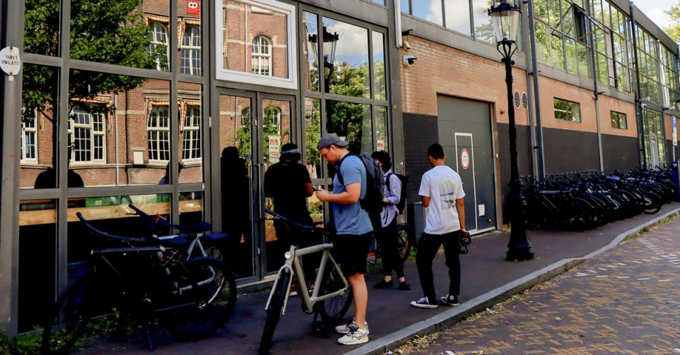 Mensen staan voor een gesloten deur van de VanMoof-shop op de Mauritskade in Amsterdam, 12 juli 2023