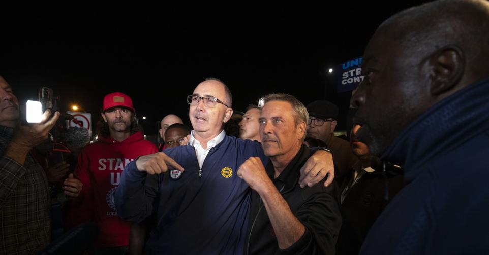 UAW-leider Shawn Fain (L) met een van de stakende arbeiders.